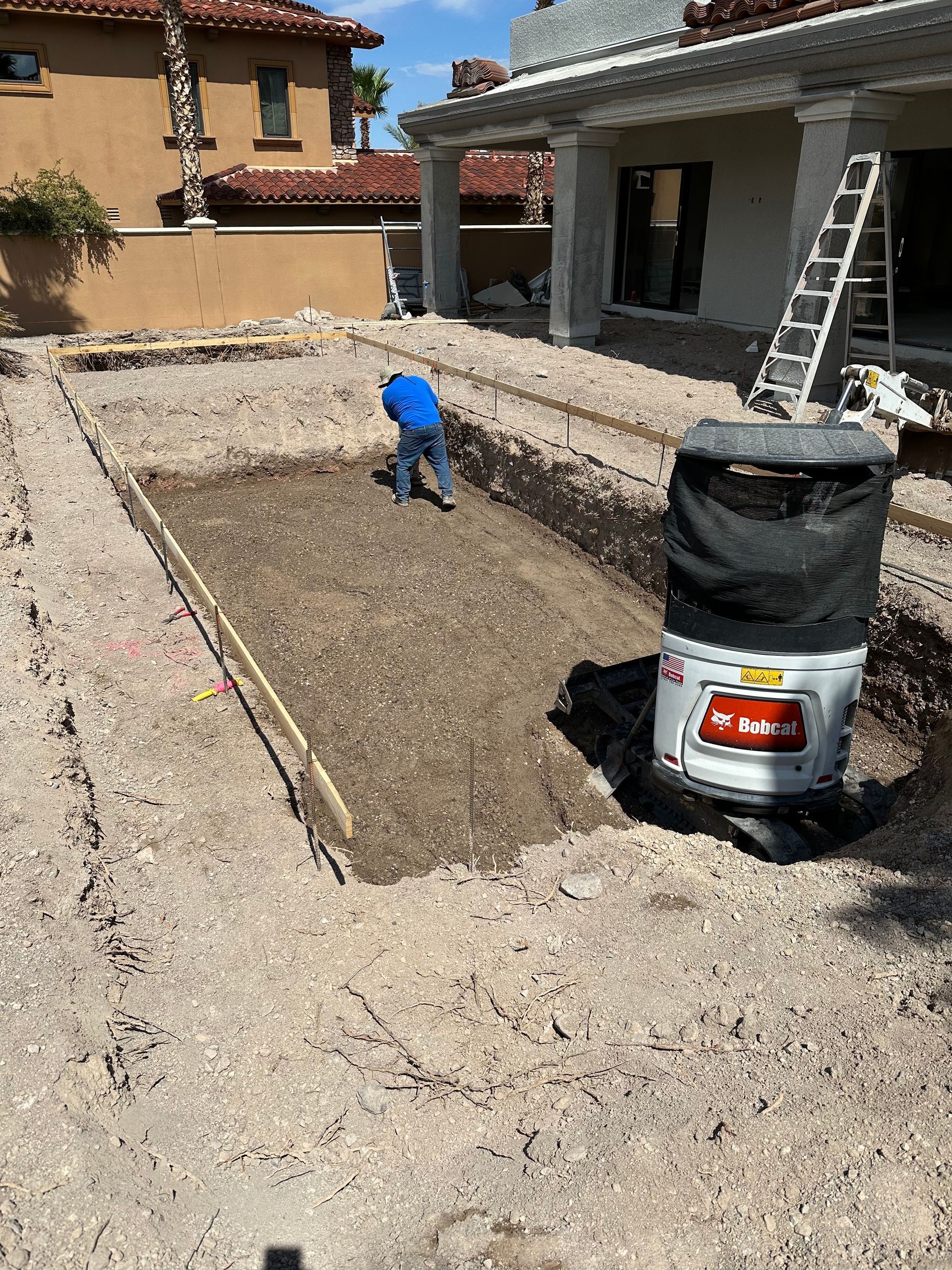 A man is digging a hole in the dirt in front of a house.