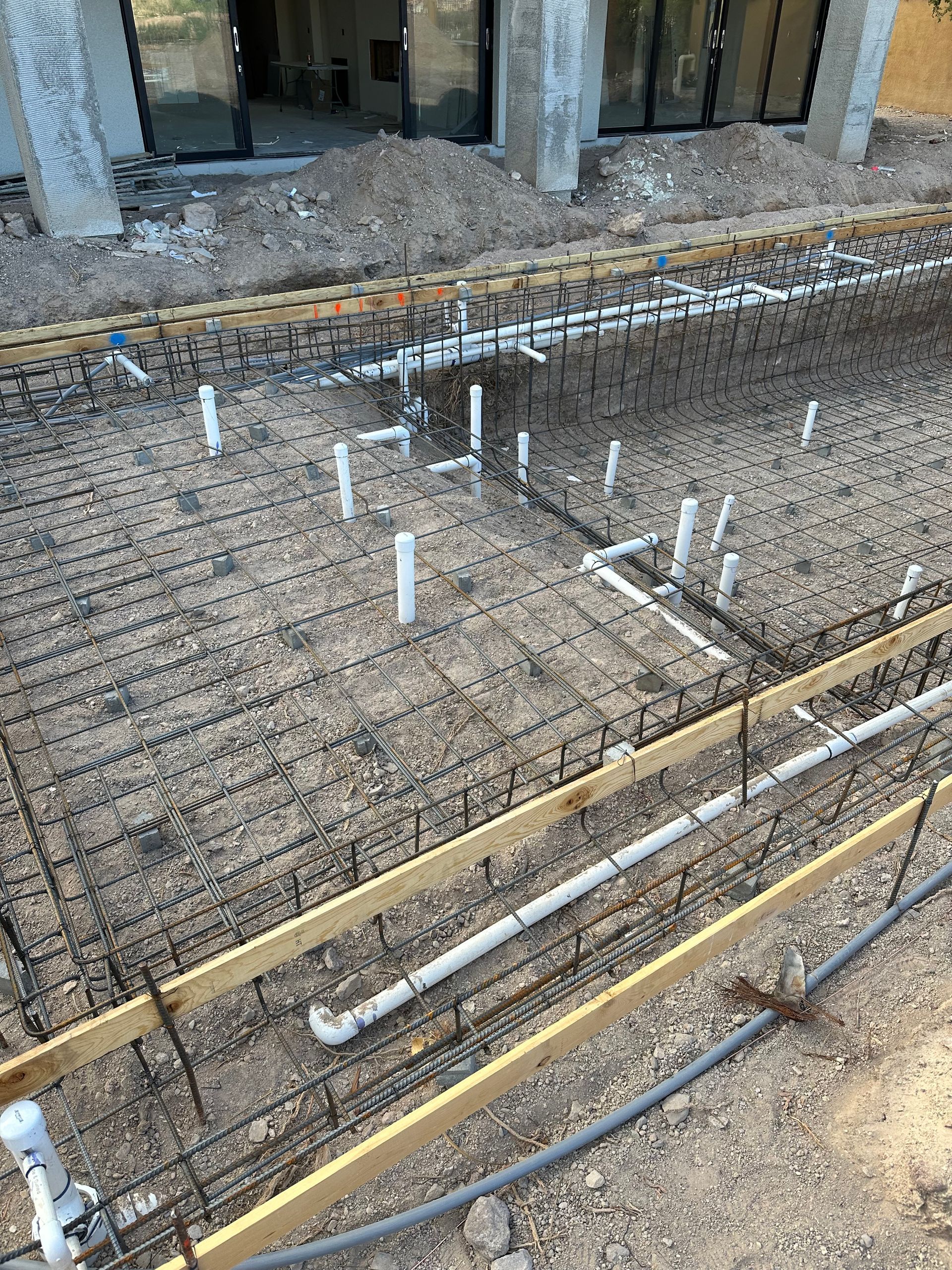 A bunch of pipes are laying on the ground on a construction site.