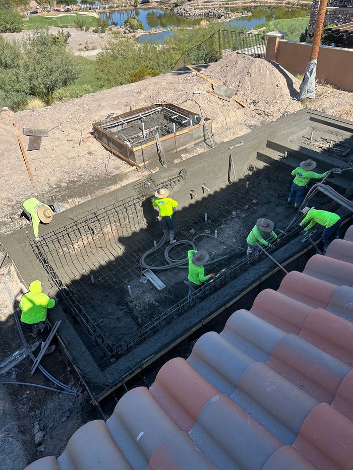 A group of construction workers are working on a concrete slab