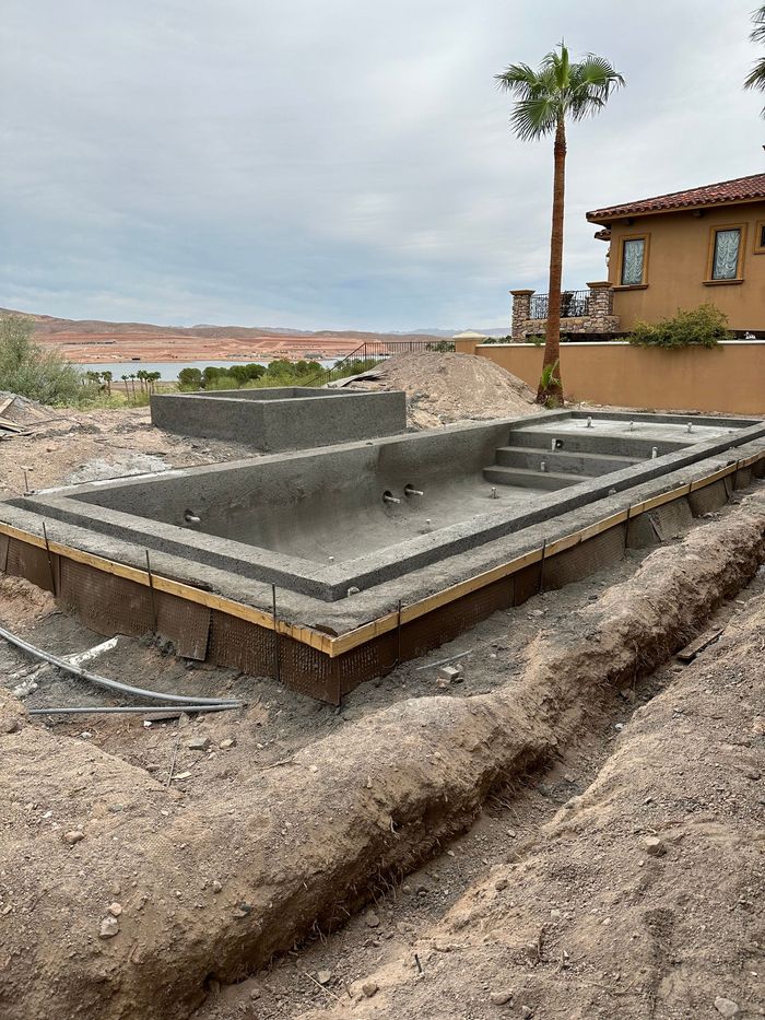 A large concrete pool is being built in front of a house