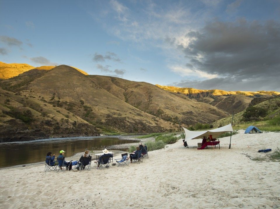 Group of People Sitting Around Campfire on A Sandy Beach