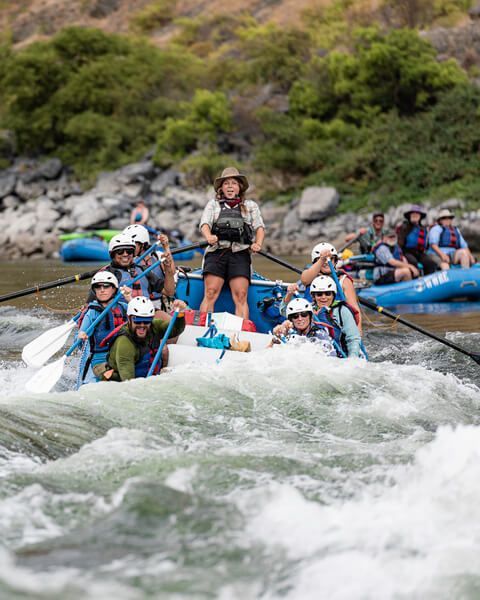 Group of People Rafting Down a River with One Woman Standing