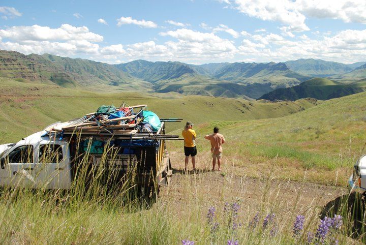 Couple of People Standing in A Field with Mountains in The Background