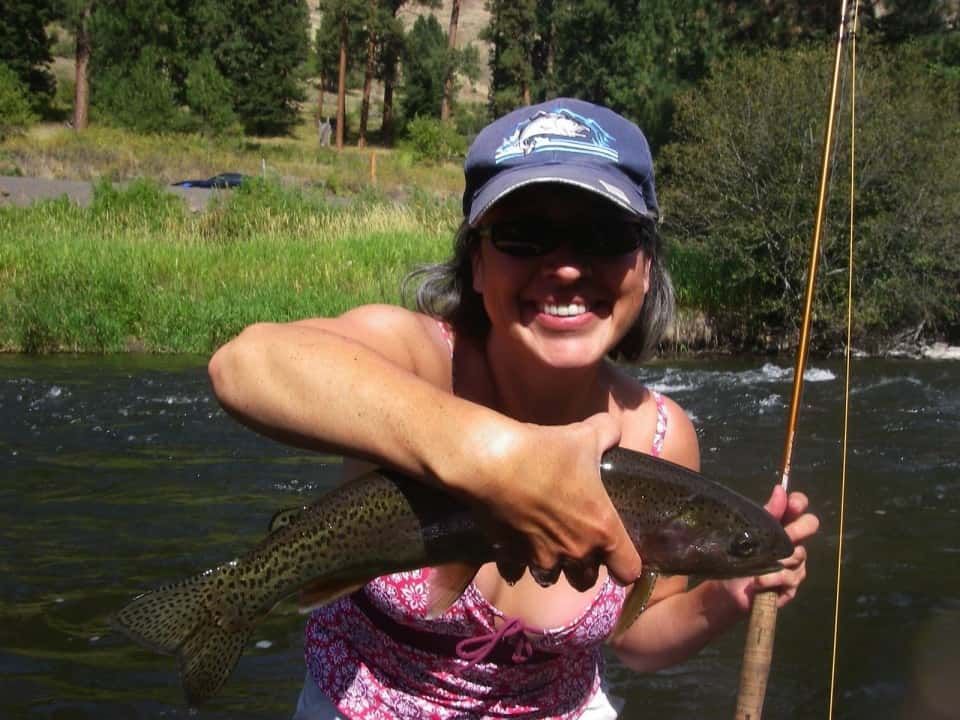 Woman Is Holding a Fish in Her Hands in A River