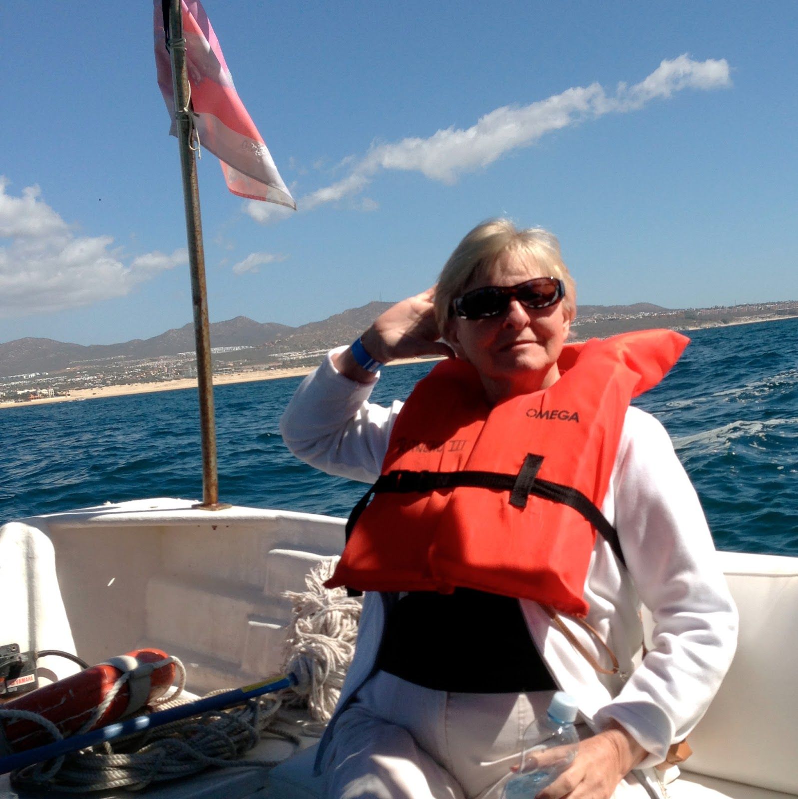 A woman on a boat wearing an orange life vest that says cormor