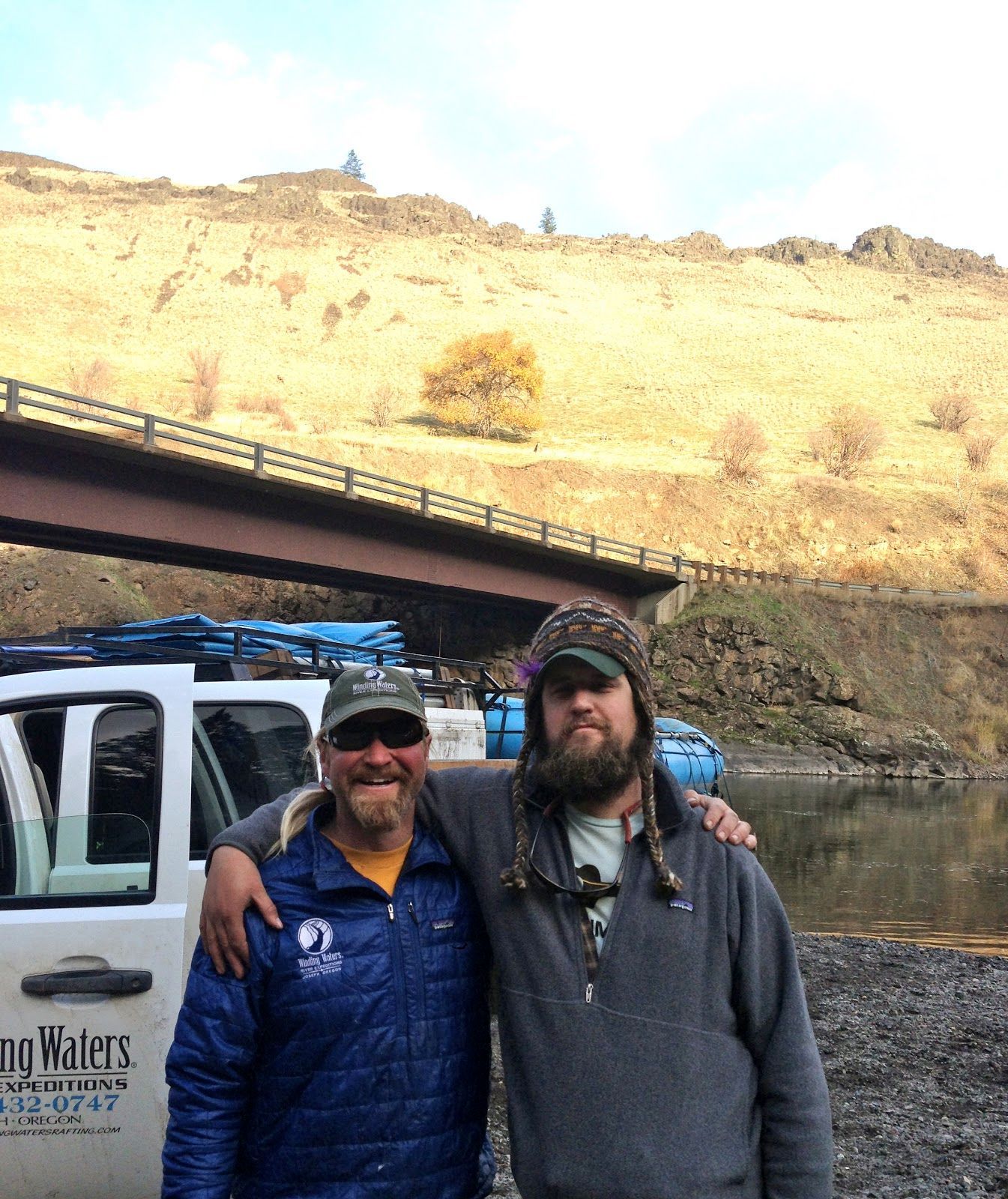 Two men are posing for a picture in front of a truck that says no waters