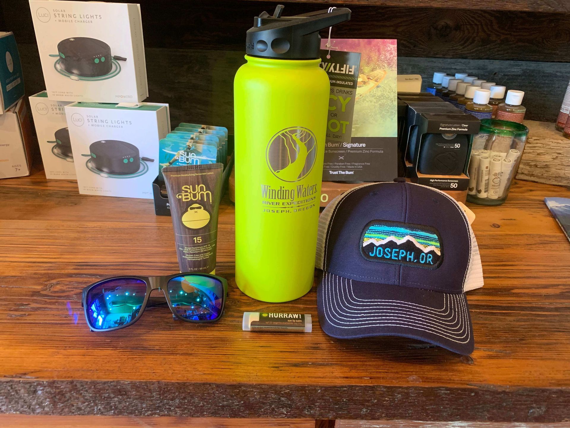 A table with a water bottle , hat , sunglasses , and other items on it.