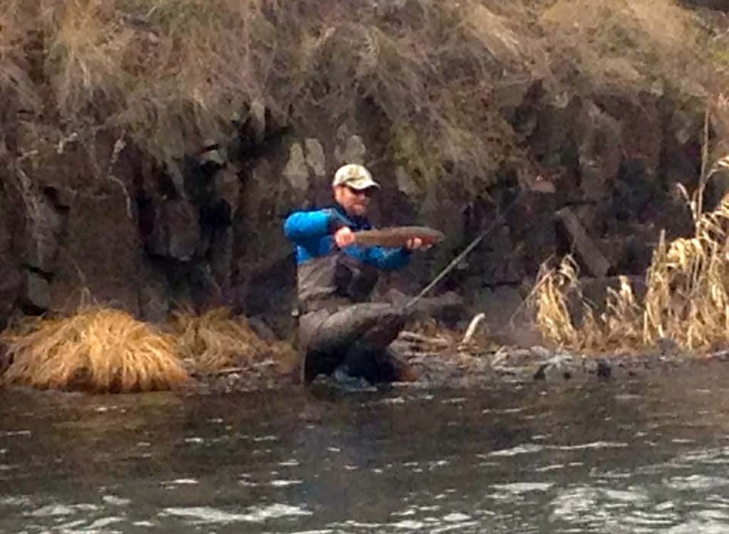 Man Kneeling in The Water Holding a Fish