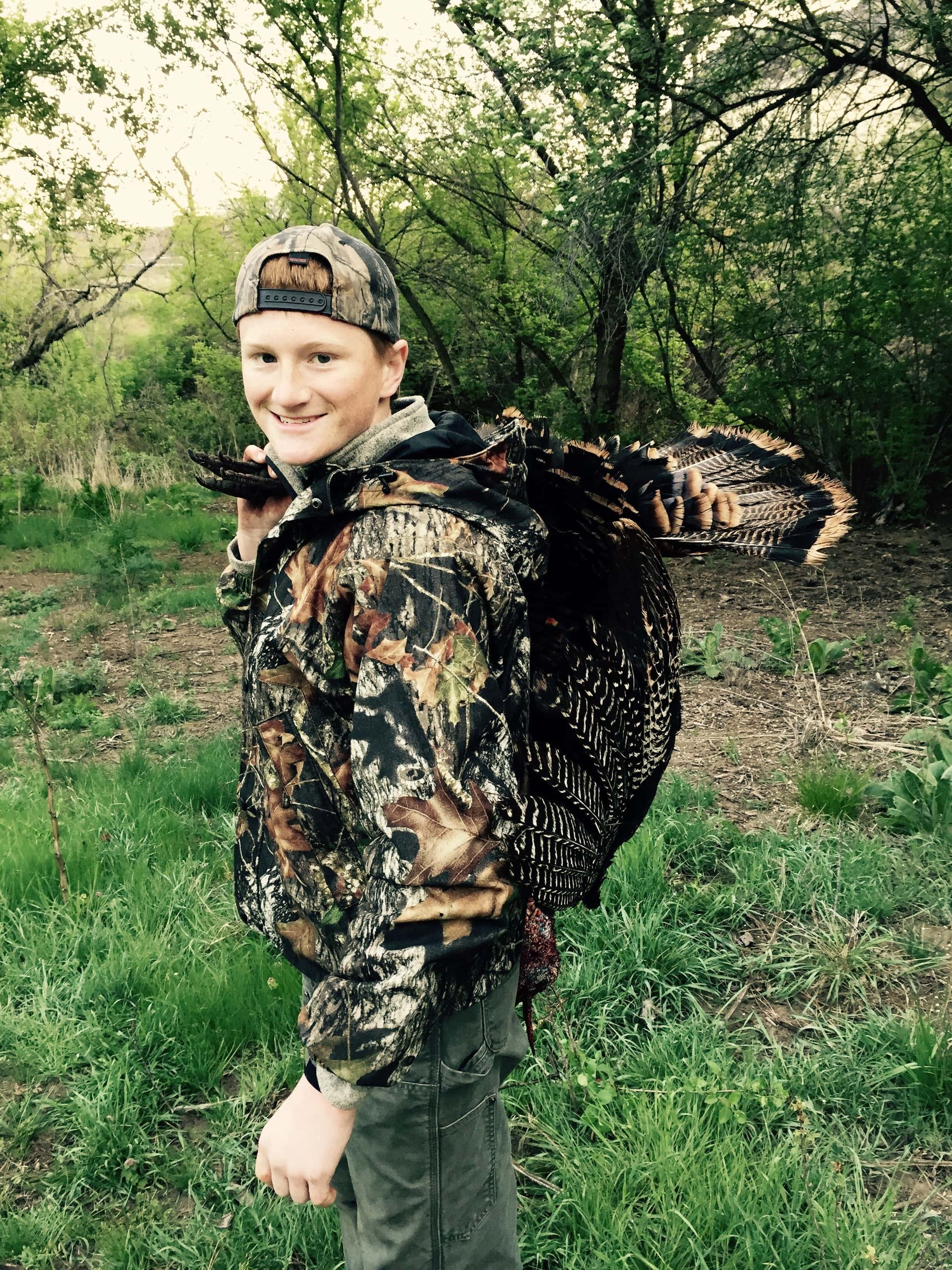 Young Boy Is Carrying a Large Turkey on His Back
