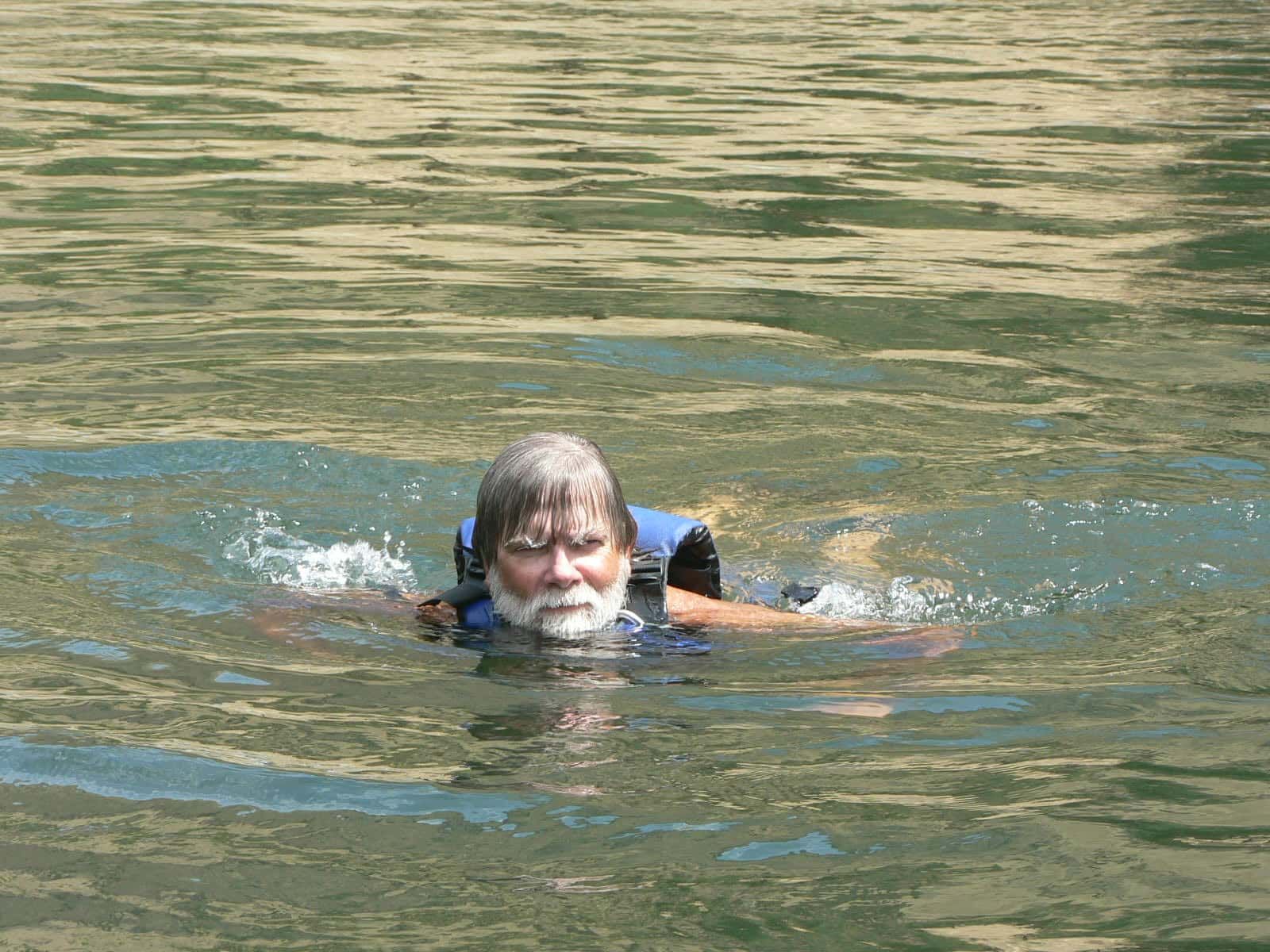 A Man in A Life Jacket Is Swimming in A Lake