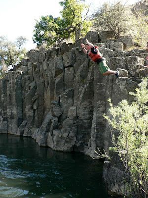 A man in a life jacket is jumping into a body of water