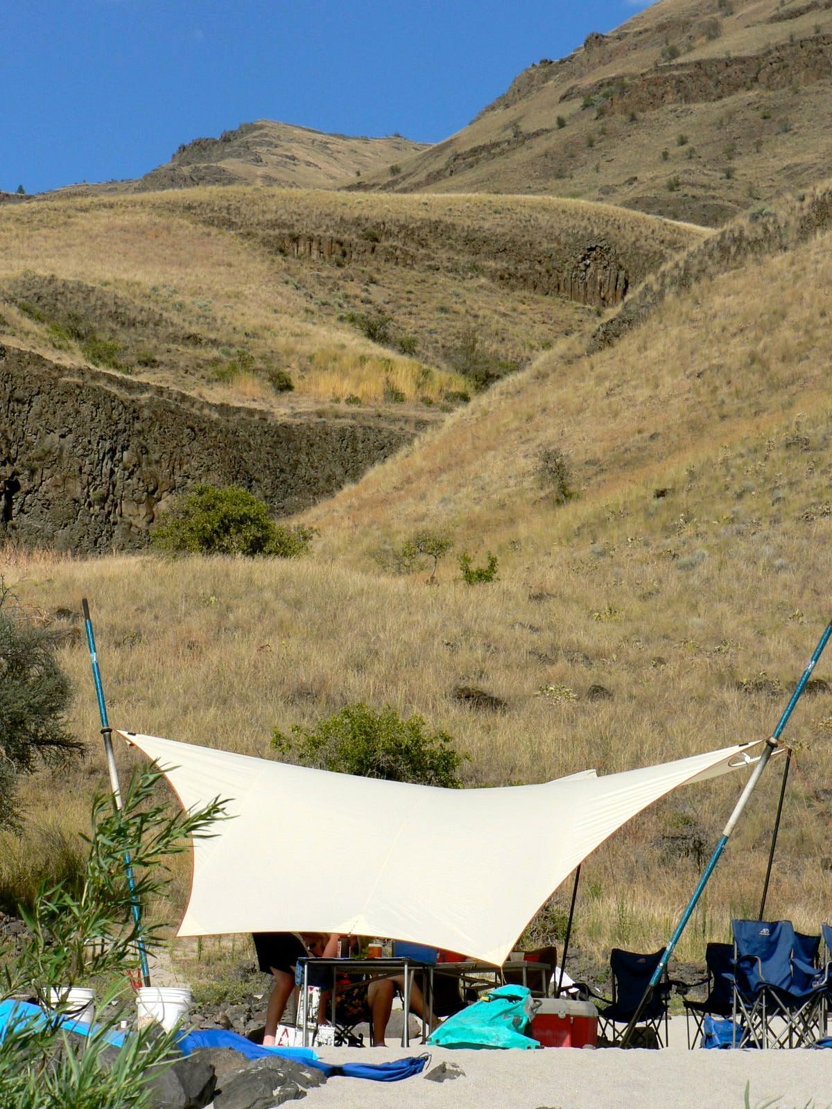 A tent is set up on a beach with mountains in the background