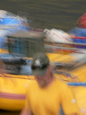 A blurry picture of a man in a yellow shirt standing next to a yellow raft.