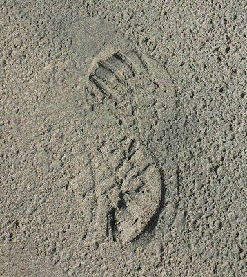 There is a footprint in the sand on the ground.