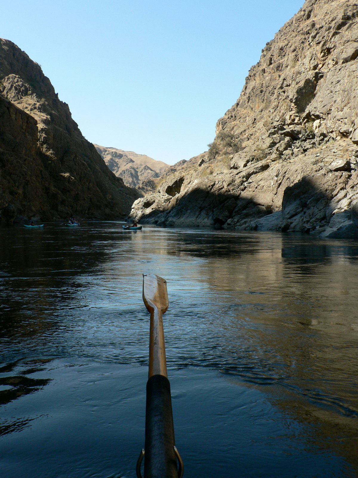 A person is rowing a boat down a river with mountains in the background