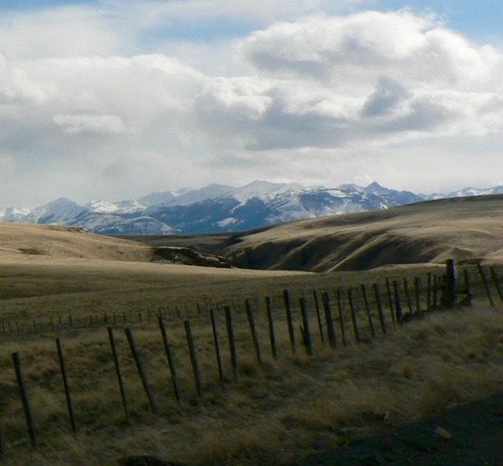 Field with A Fence and Mountains in The Background