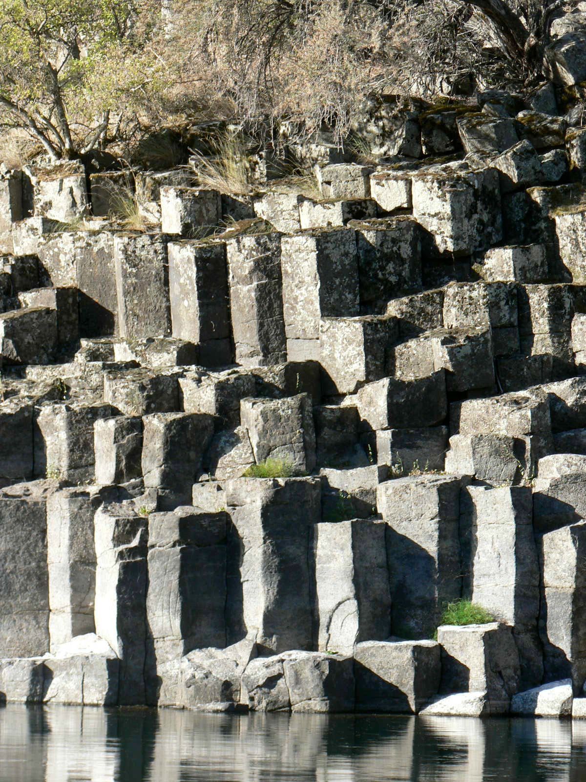 A pile of rocks sitting next to a body of water