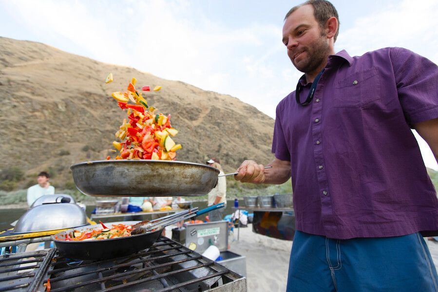 Man in Purple Shirt Is Cooking Vegetables on A Stove