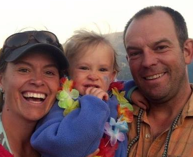 A man and woman are holding a baby and smiling for the camera