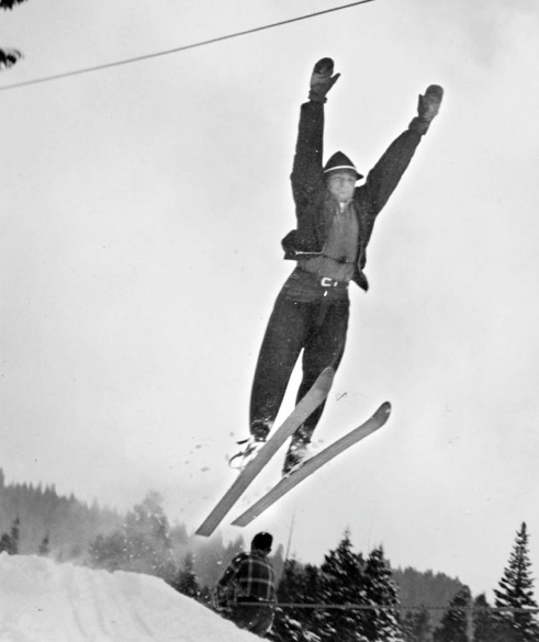 A man is skiing in the air with his arms in the air