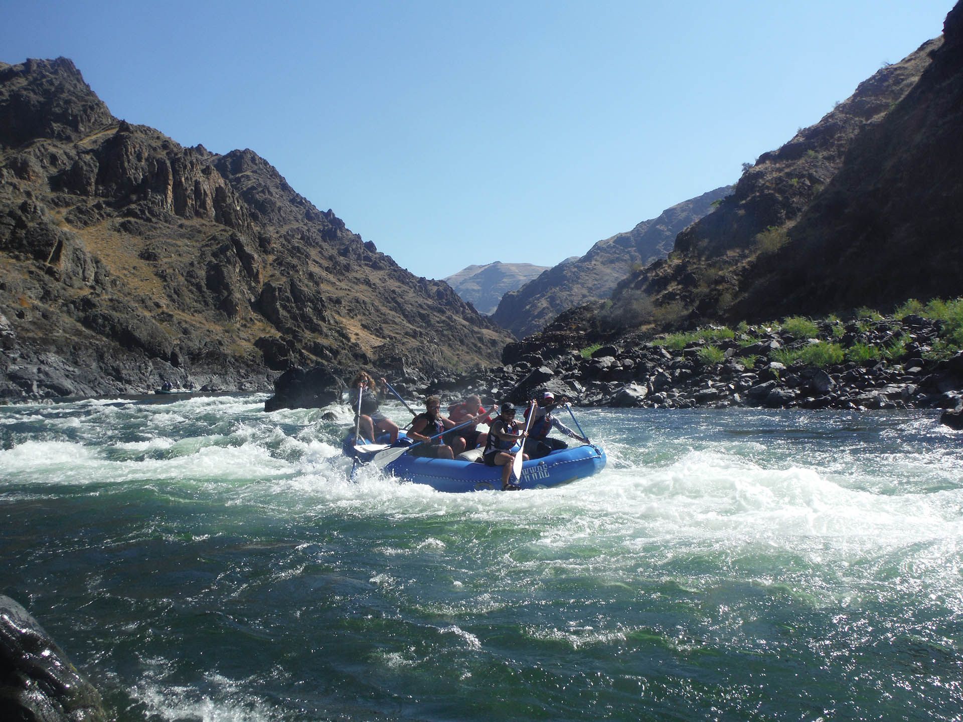 A group of people are rafting down a river with mountains in the background