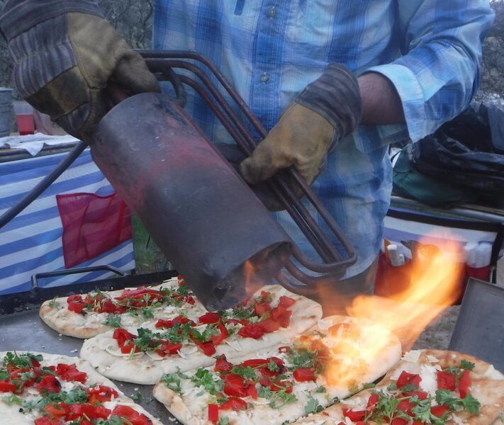 Man Using a Flamethrower to Cook Pizza