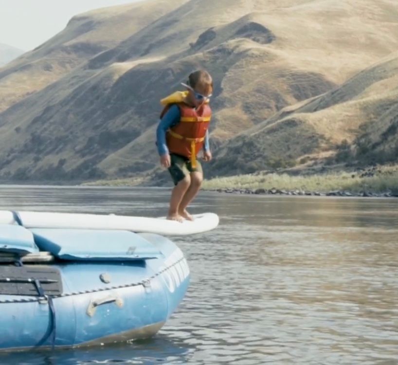 Kid in A Life Jacket isJumping Off a Raft Into the Water