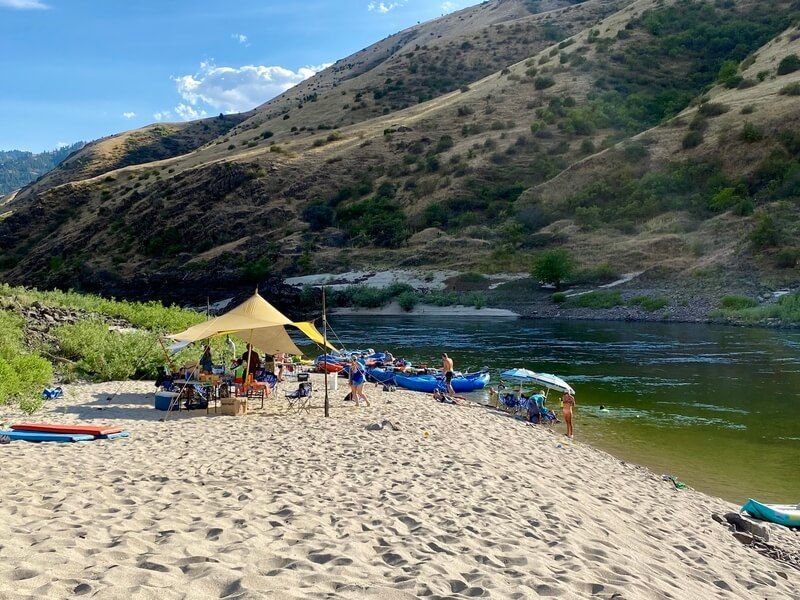 People Set Camp on A Sandy Beach Next to A River