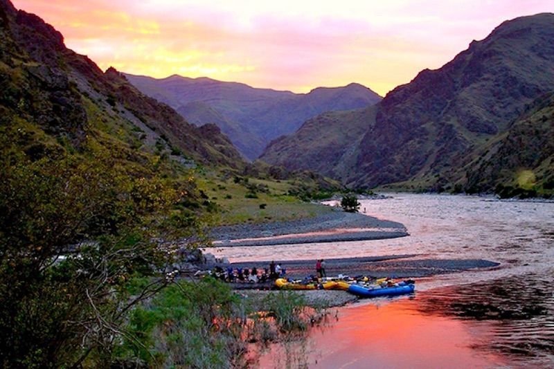 Group of people beside river with mountains in the background