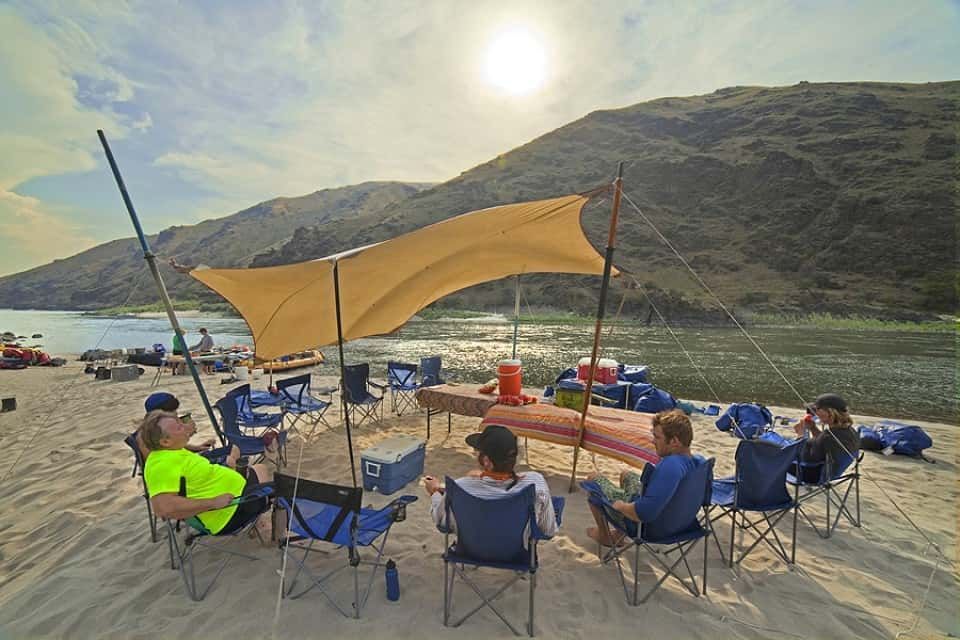 Group of People Sitting Under a Canopy on A Beach