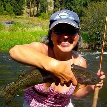 Woman Holding a Fish in Her Hands in A River