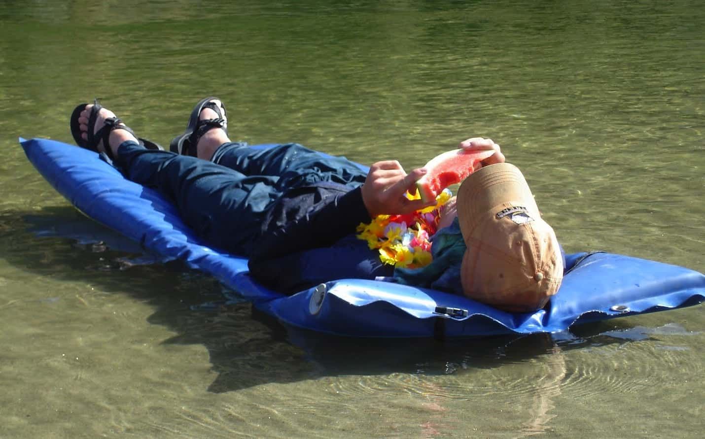 Person Laying on A Blue Raft in The Water