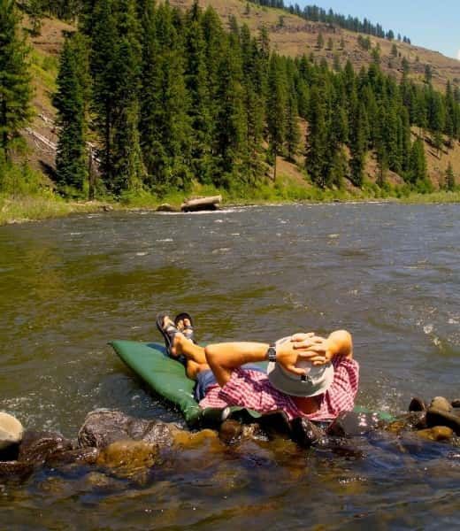 Person Laying on A Green Raft in A River