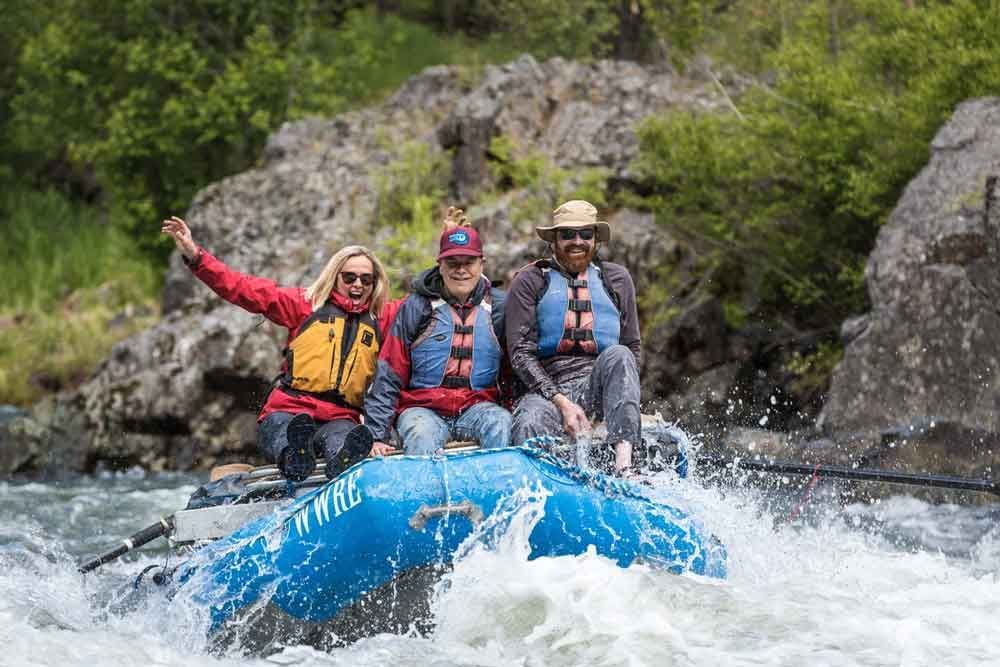 Group of People Are Riding a Raft Down a River