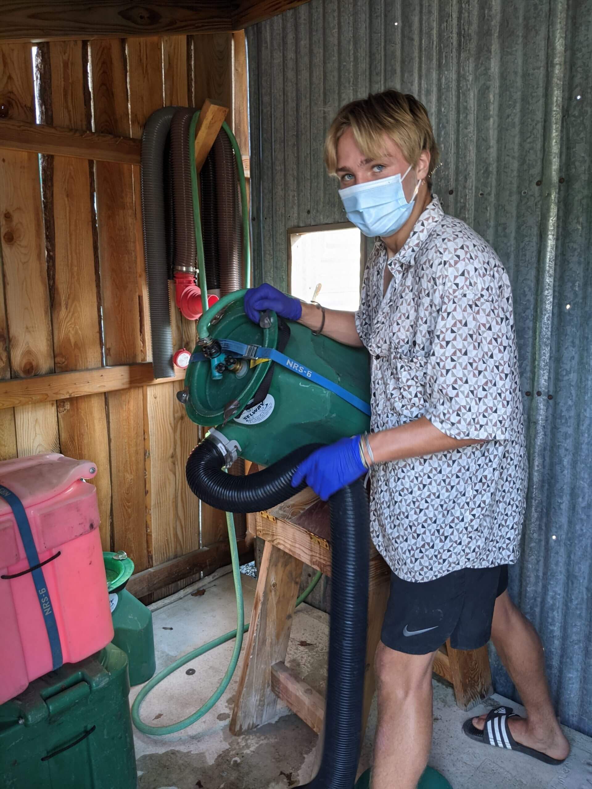 Man Wearing a Mask Is Using a Vacuum Cleaner in A Shed