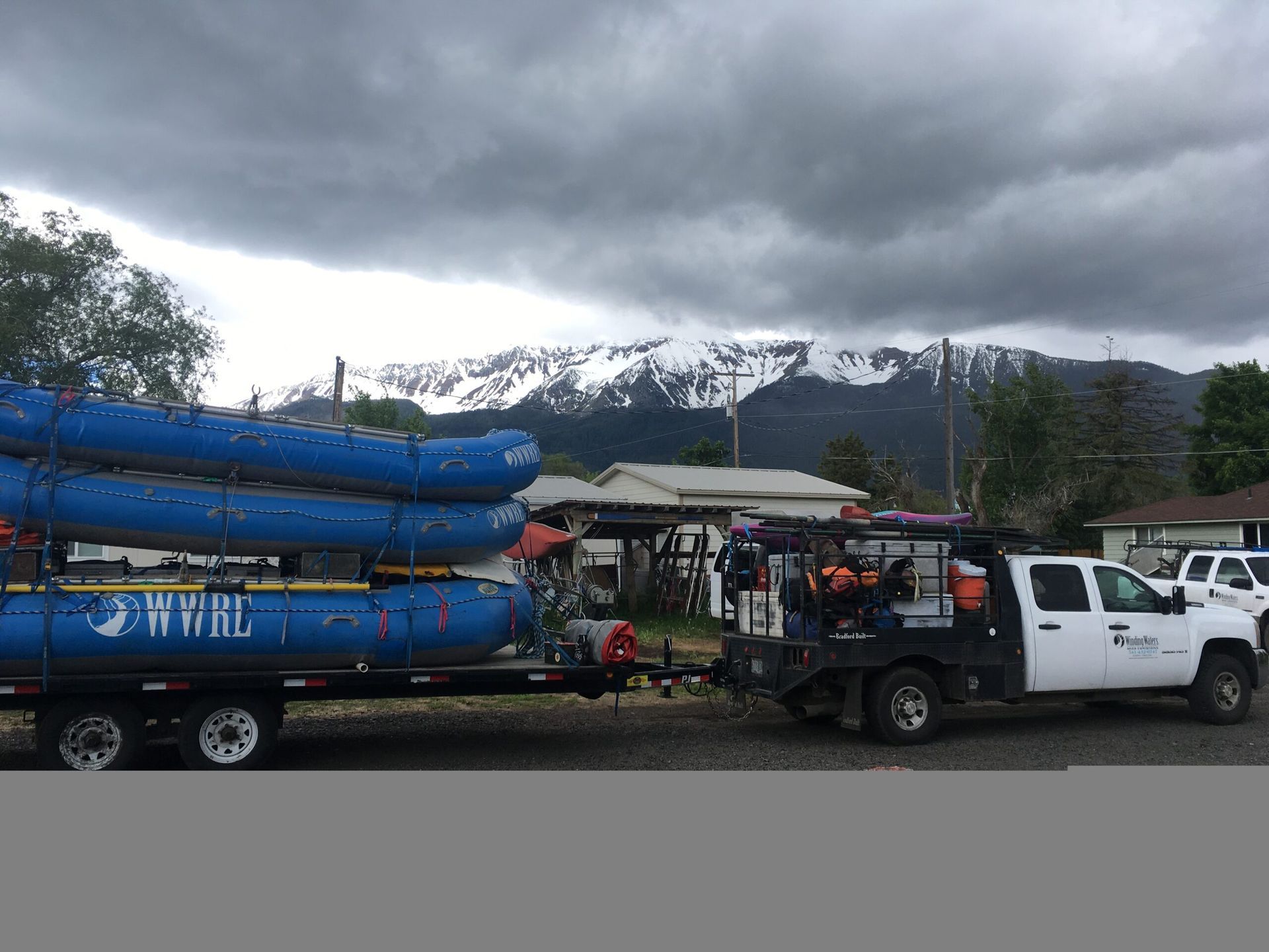 White Truck is Towing a Trailer with Blue Rafts on It