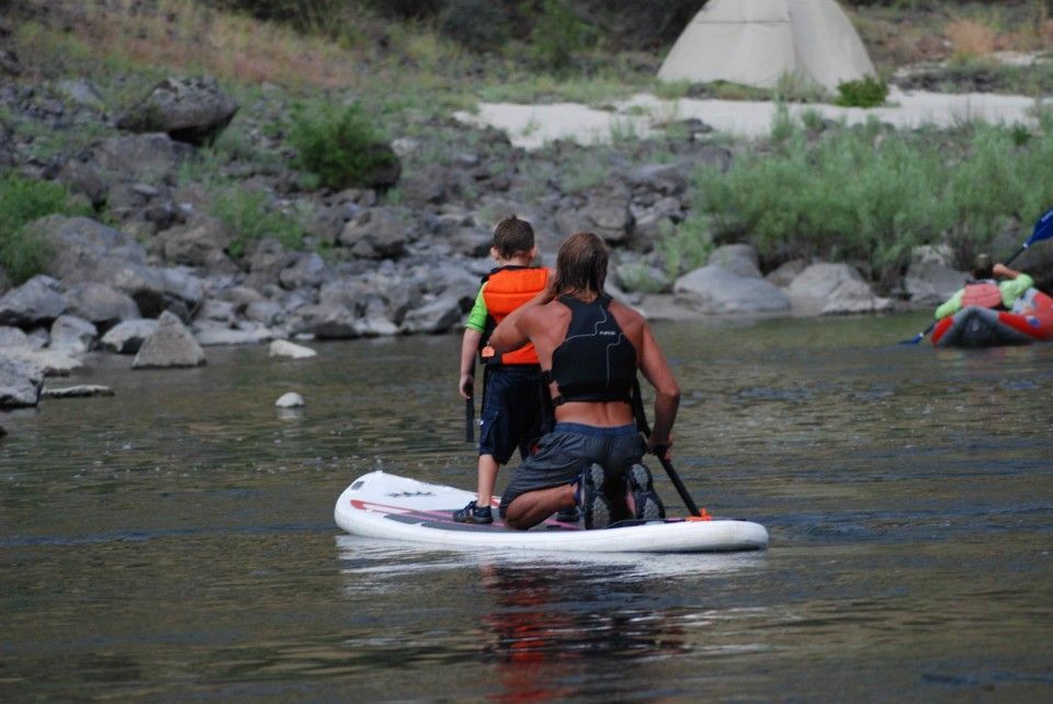 Man and Two Children Are Kneeling on A Paddle Board in A River