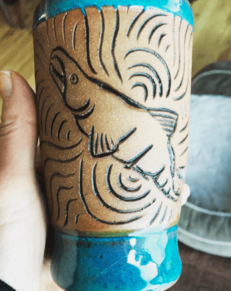 Person Holding a Blue Vase with A Fish on It