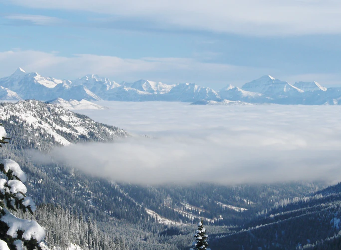 A view of a snowy mountain range covered in clouds.