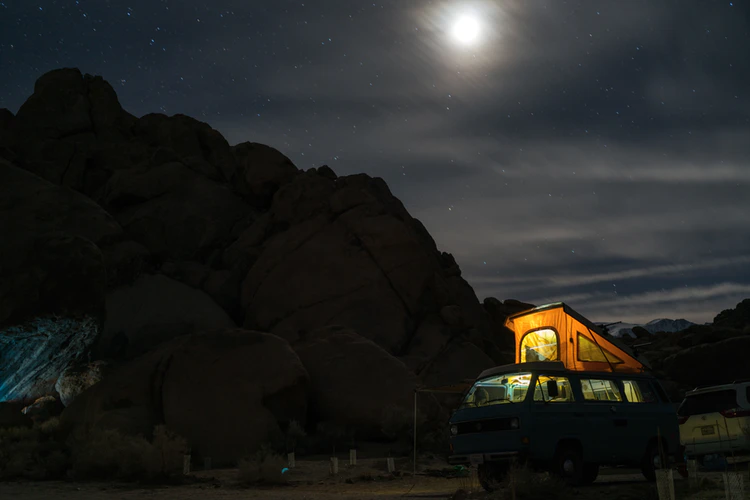 Van with A Tent on Top of It Is Parked in Front of A Mountain at Night
