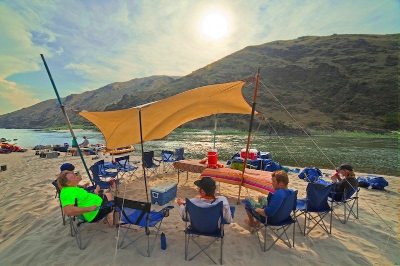 A group of people are sitting under a canopy on a beach.