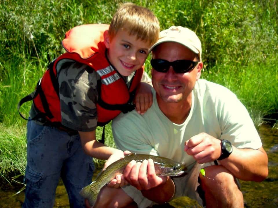 Man and A Boy Are Holding a Fish in Their Hands