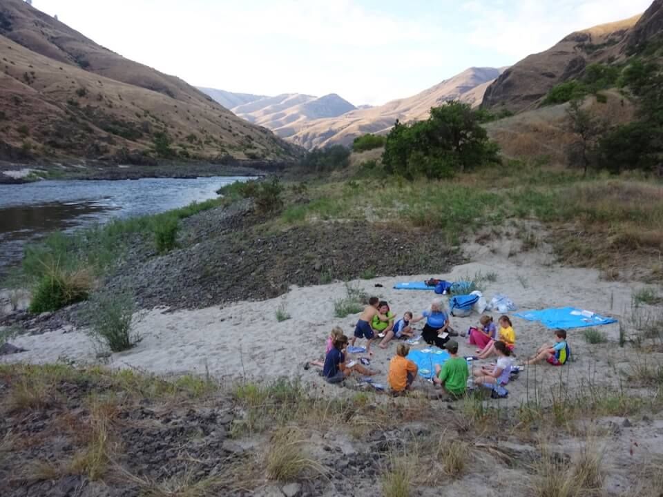 People Sitting in A Circle on The Ground Near a River