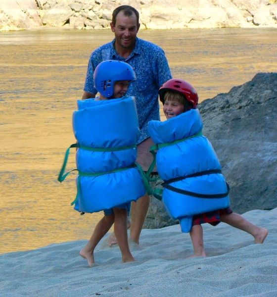 Man and Two Children Wearing Life Jackets and Helmets