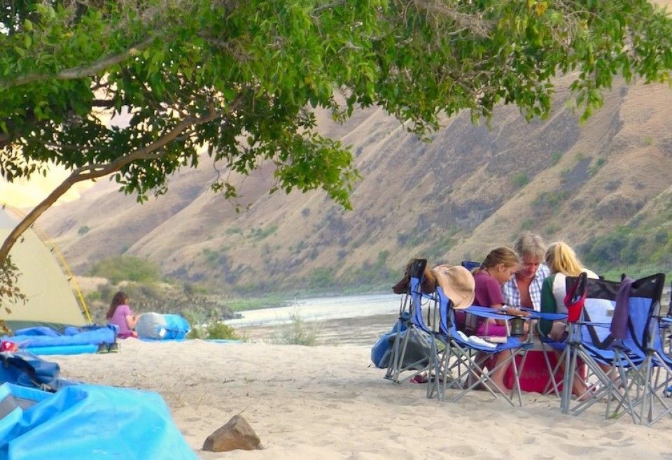 a group of people are sitting at a table on a beach .