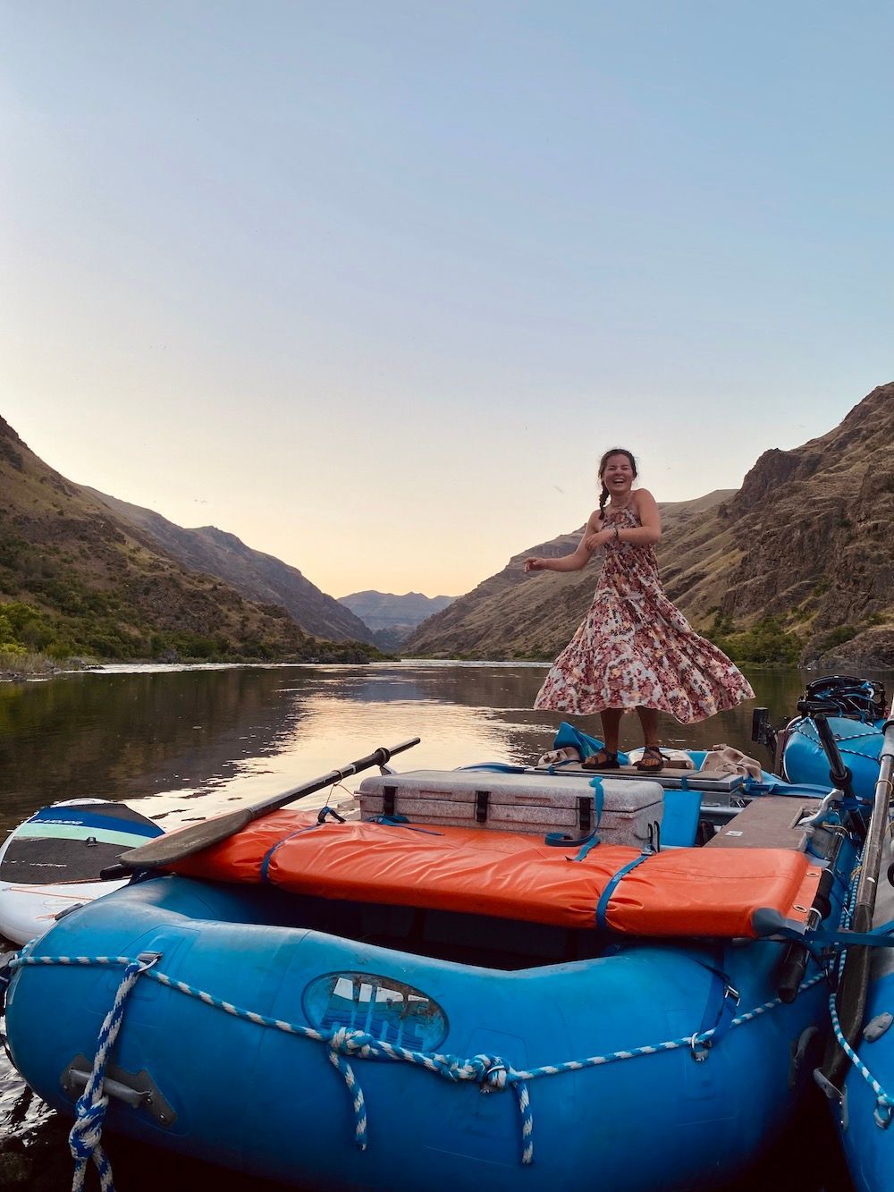 Woman in A Dress Is Standing on Top of A Blue Raft on A River
