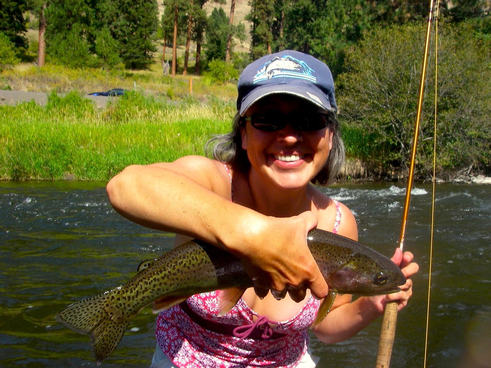 A woman is holding a rainbow trout in her hands