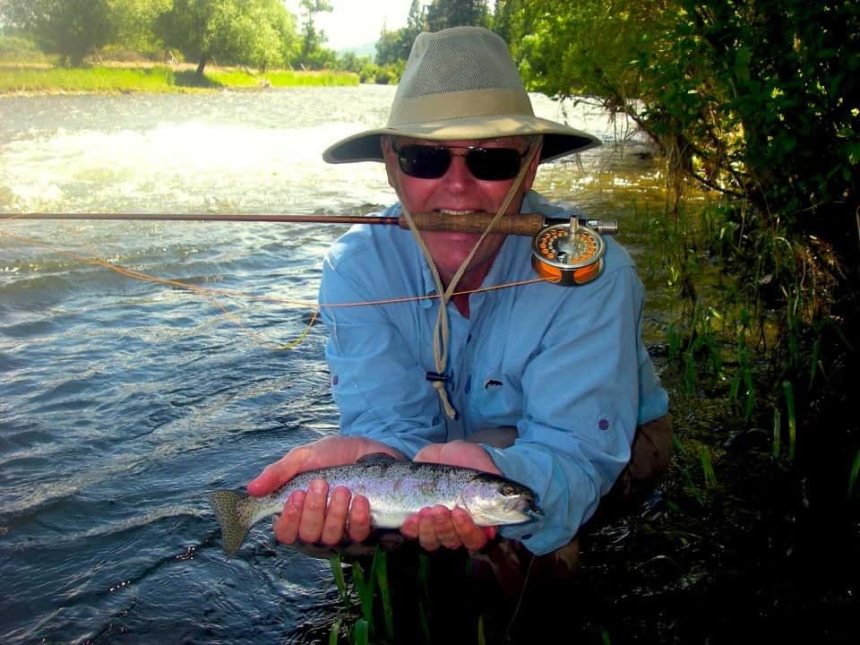 Man in A Hat Is Holding a Fish in His Hands