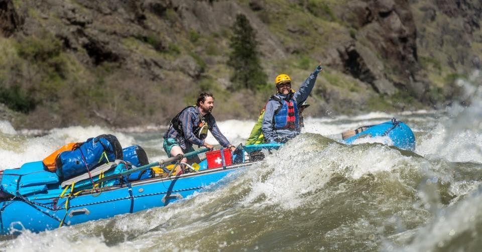 people in a blue raft going up rapids