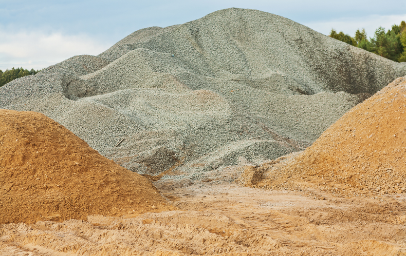 A pile of gravel and sand is sitting on top of a dirt hill.
